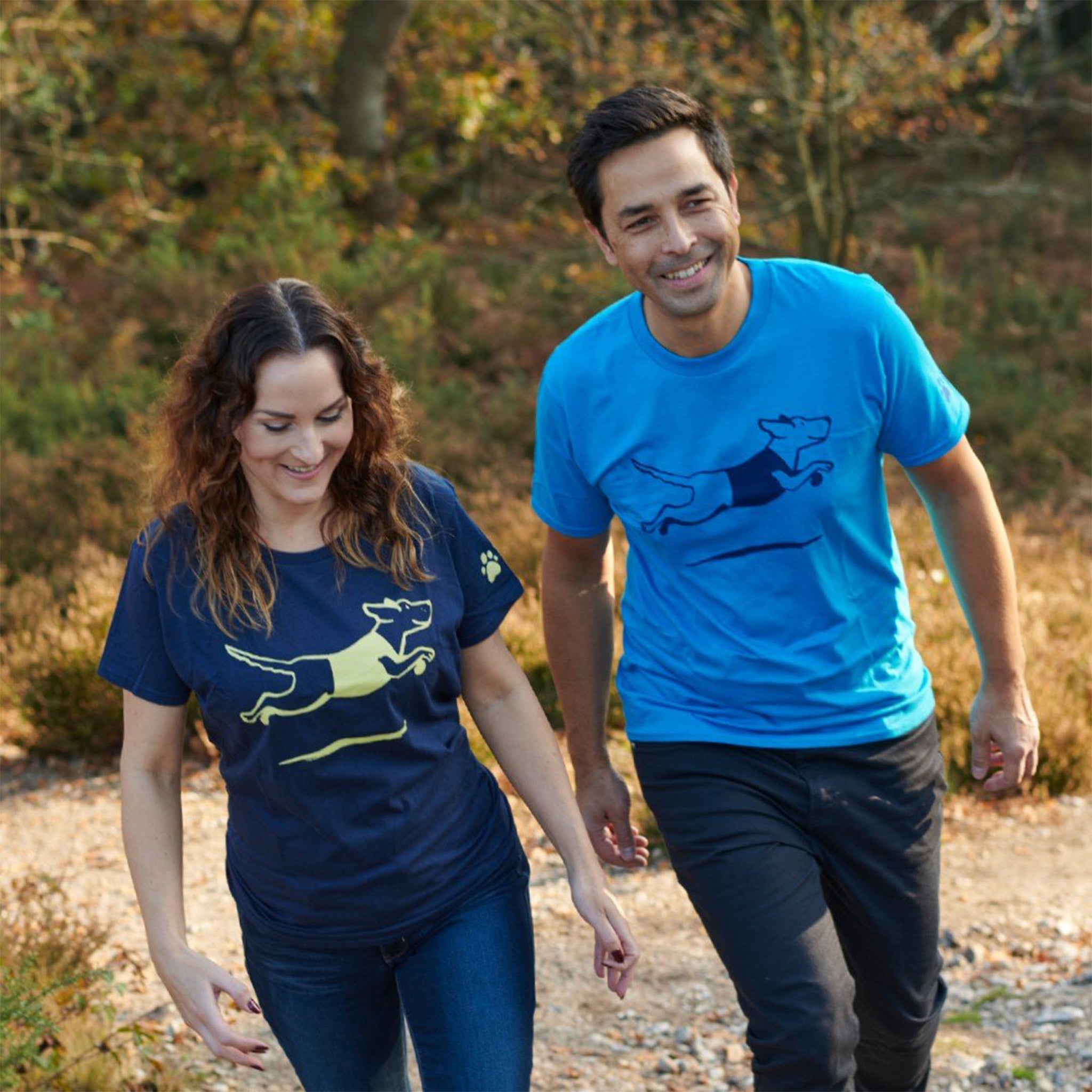 A lifestyle image of a couple wearing the Navy and Light Blue Guide Dogs T-shirts.