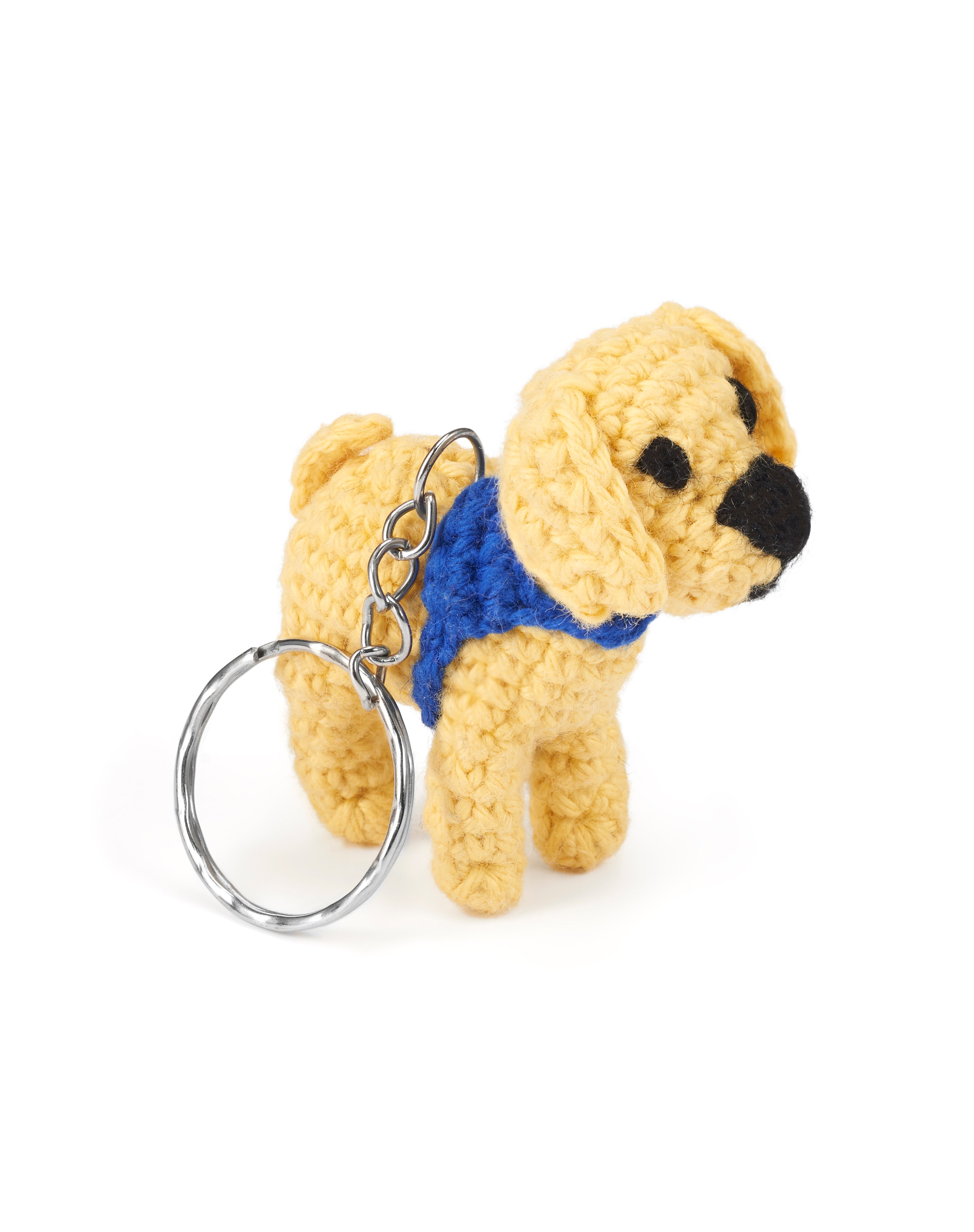 A crocheted yellow labrador wearing a blue dog coat on a metal keyring.