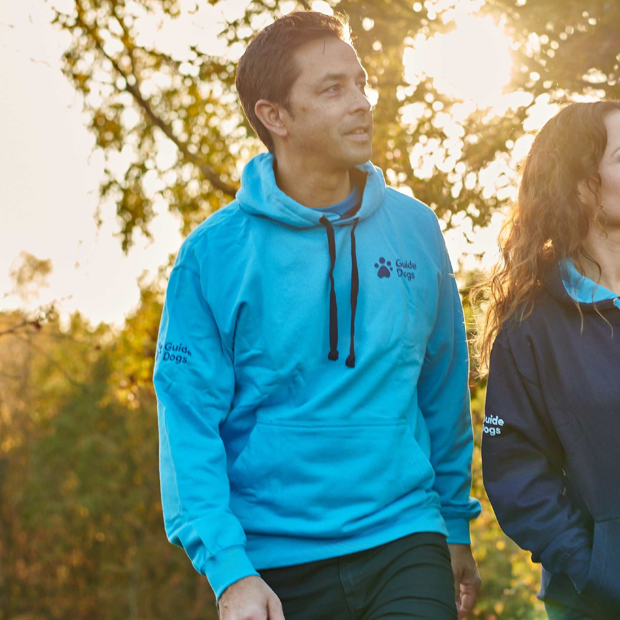 Images shows a man and woman wearing Guide Dogs hoodies. 